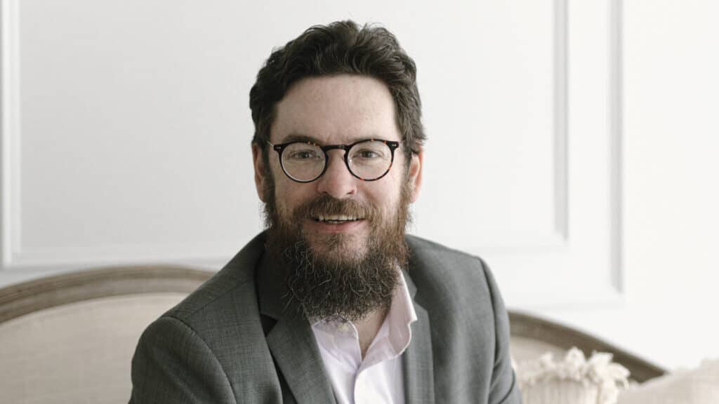 A photograph of Neil Fitzroy, Managing Director - Australasia for Oxford International Education Group - sitting on a sofa infront of a neutral wall