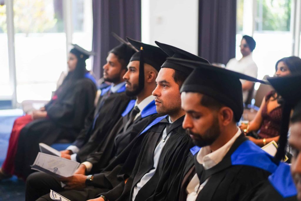 Graduates seated in academic gowns during a graduation ceremony.