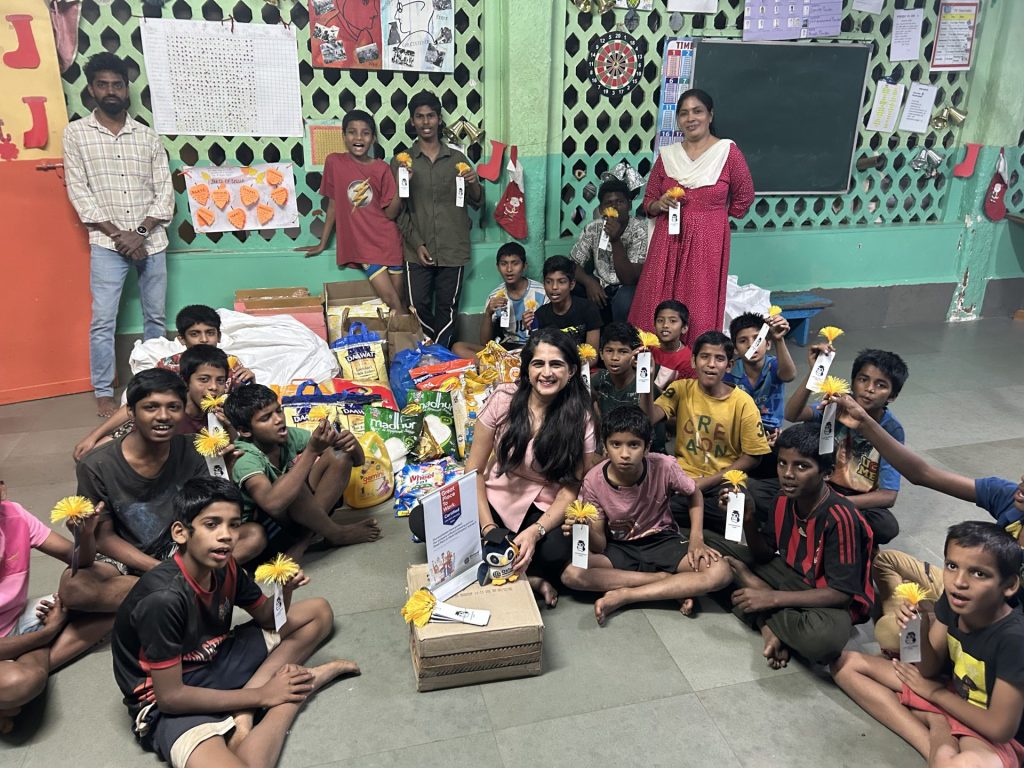 A Oxford International employee sitting with a group of children showing off the certificate of contribution