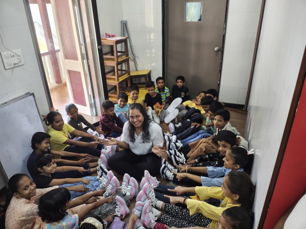Oxford International employee surrounded by children pointing that their shoes