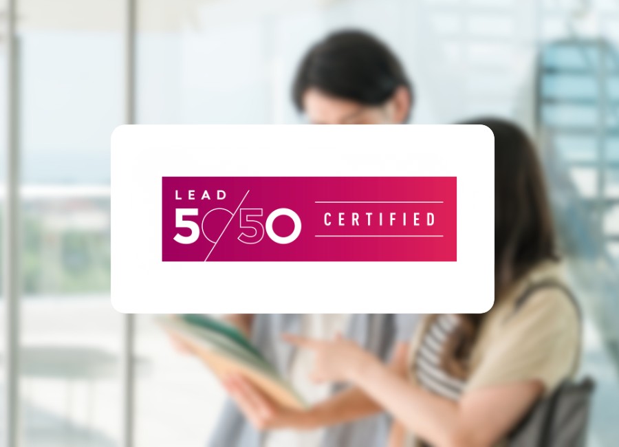 Lead 50/50 Certified logo displayed over a blurred image of two students reading together.