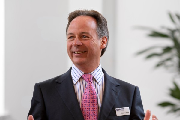 A photo of Robert Darell, co-founder of Oxford International, smiling and looking off camera. He is in front of a generic office background